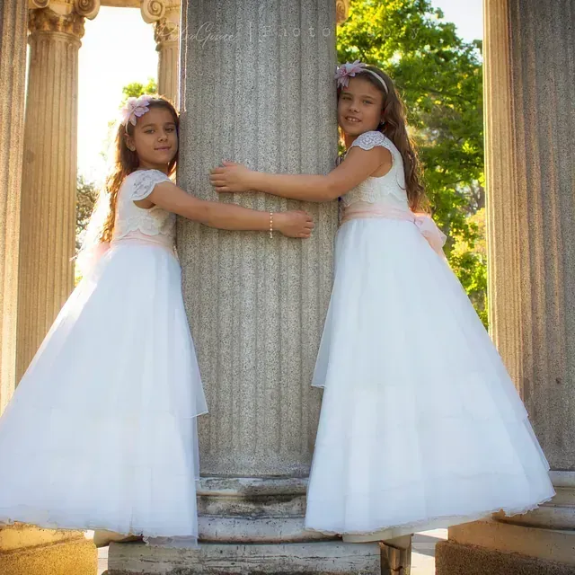 Dos niñas con vestidos blancos se abrazan