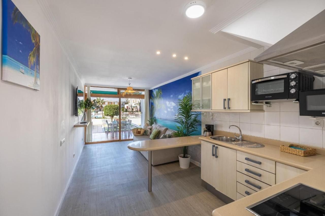 Una cocina con estufa, fregadero, microondas y un cuadro en la pared.