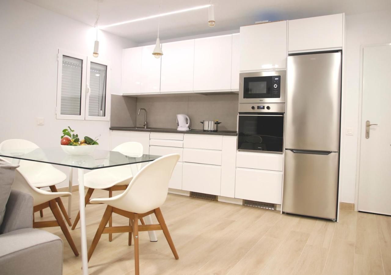 Una cocina con gabinetes blancos y un refrigerador de acero inoxidable.