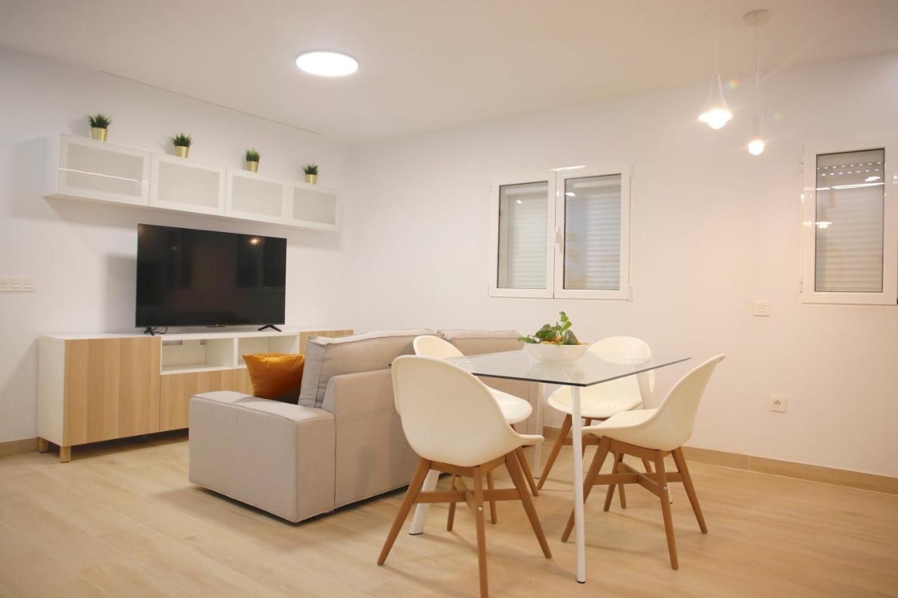 Una sala de estar con sofá, mesa y sillas y un televisor de pantalla plana.