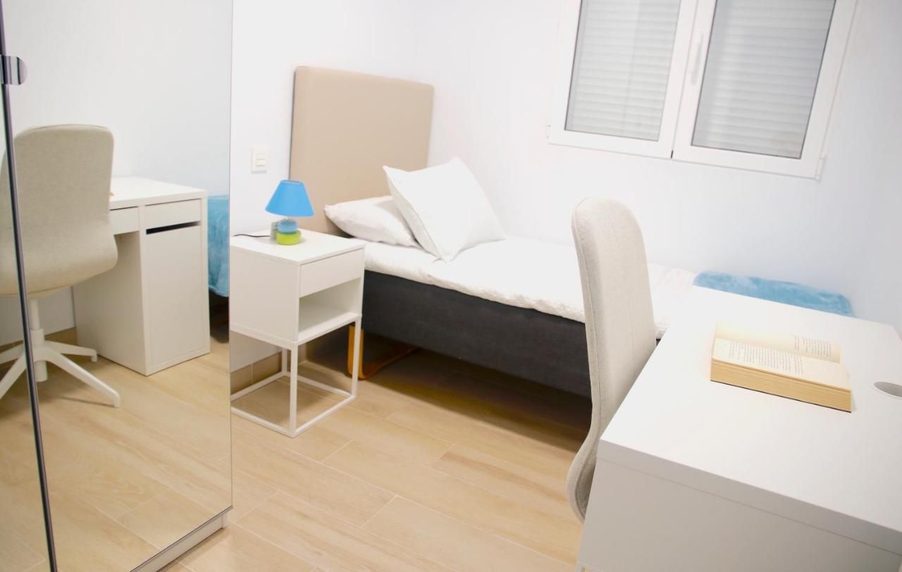 Un dormitorio con una cama individual, escritorio, silla y mesita de noche.