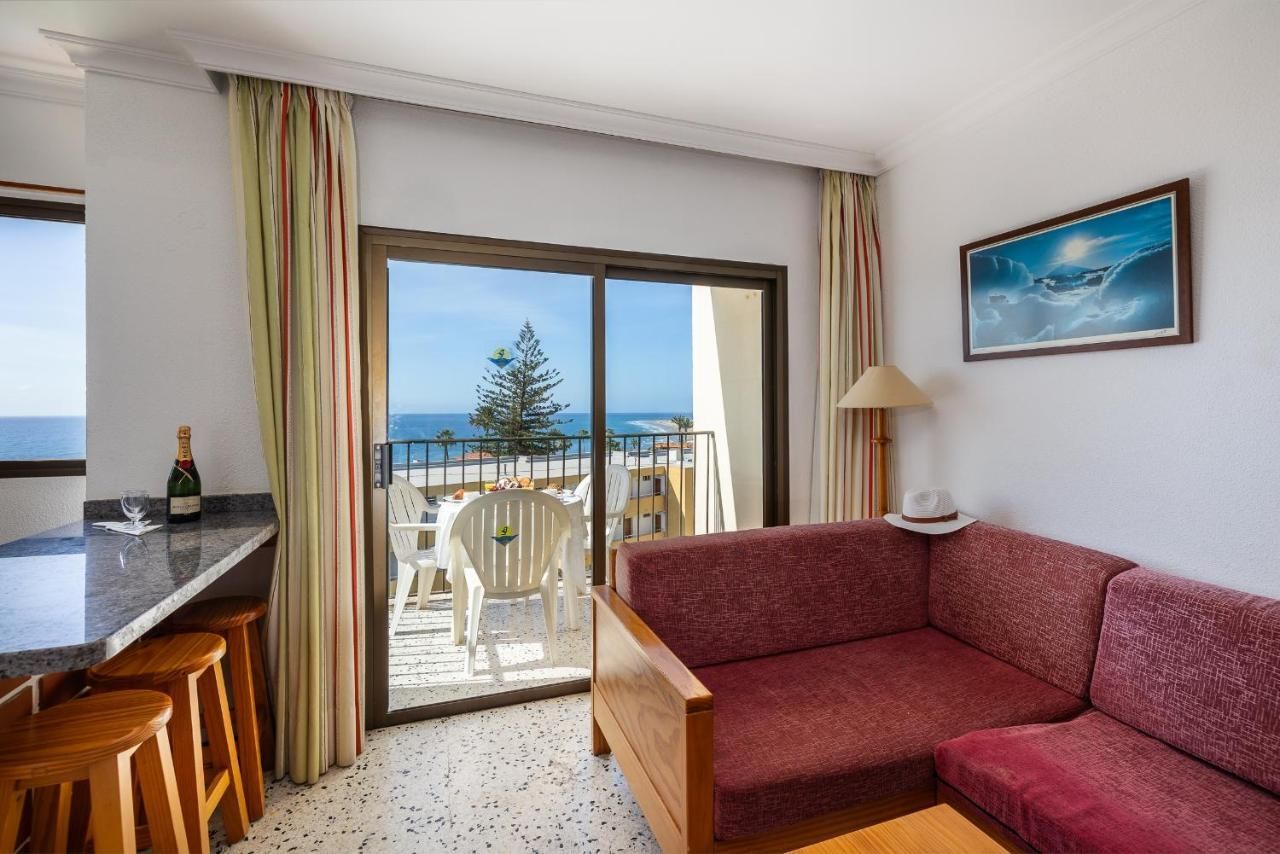 Una sala de estar con un sofá y un balcón con vista al mar.