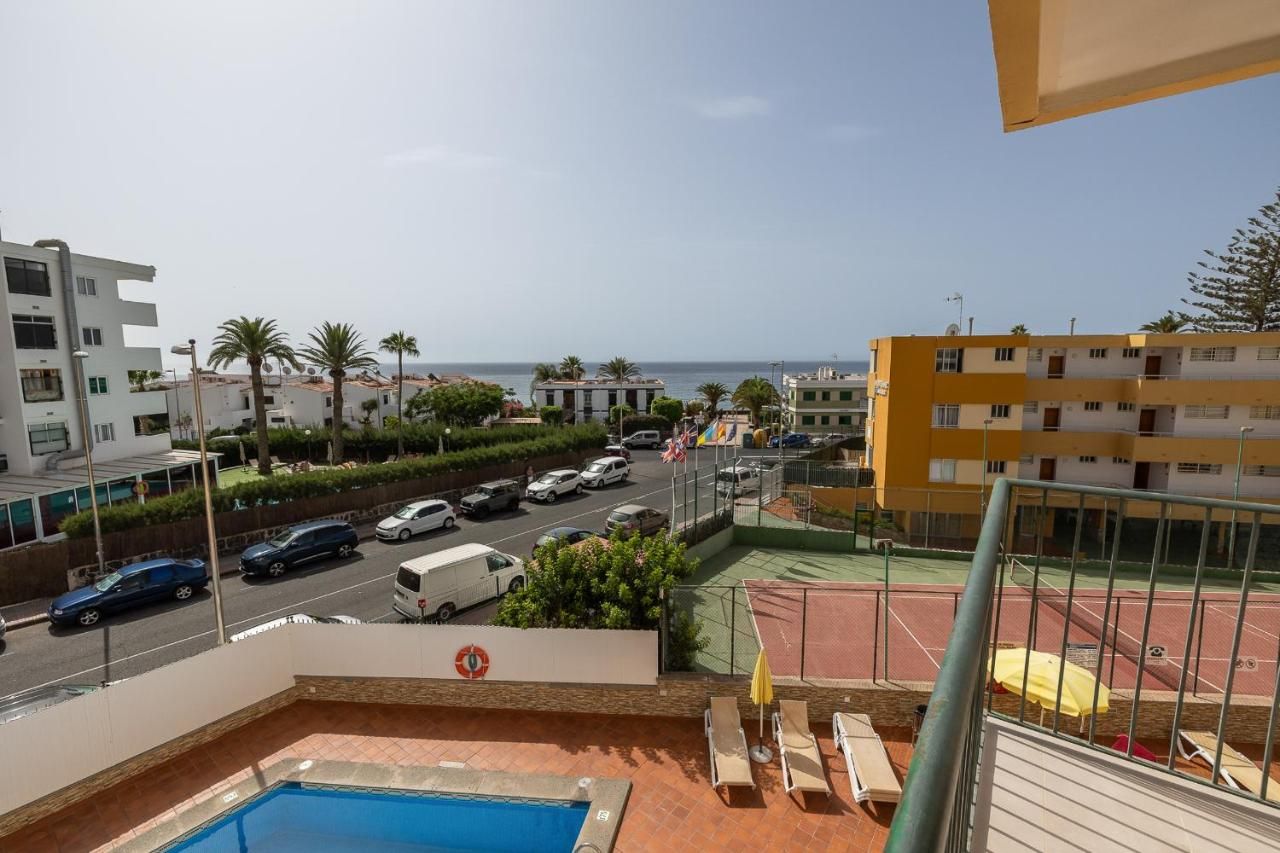 Una vista de una piscina y una cancha de tenis desde un balcón.