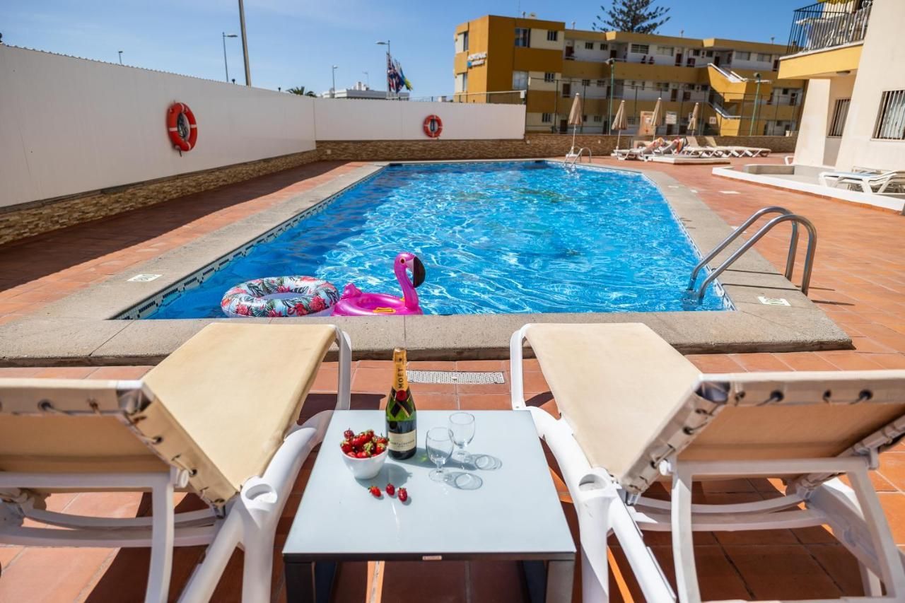 Una piscina con una mesa y sillas delante de ella.