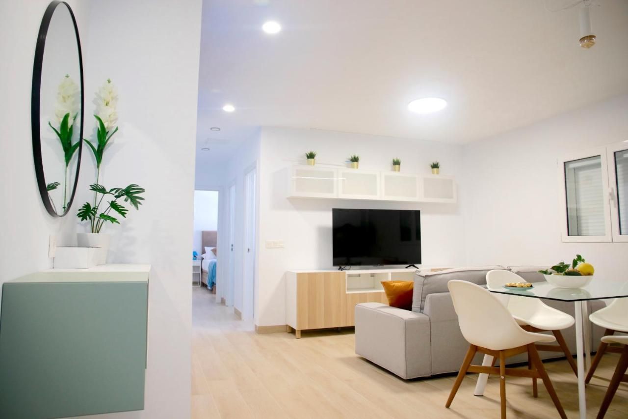 Una sala de estar con un sofá, una mesa, sillas y un televisor.