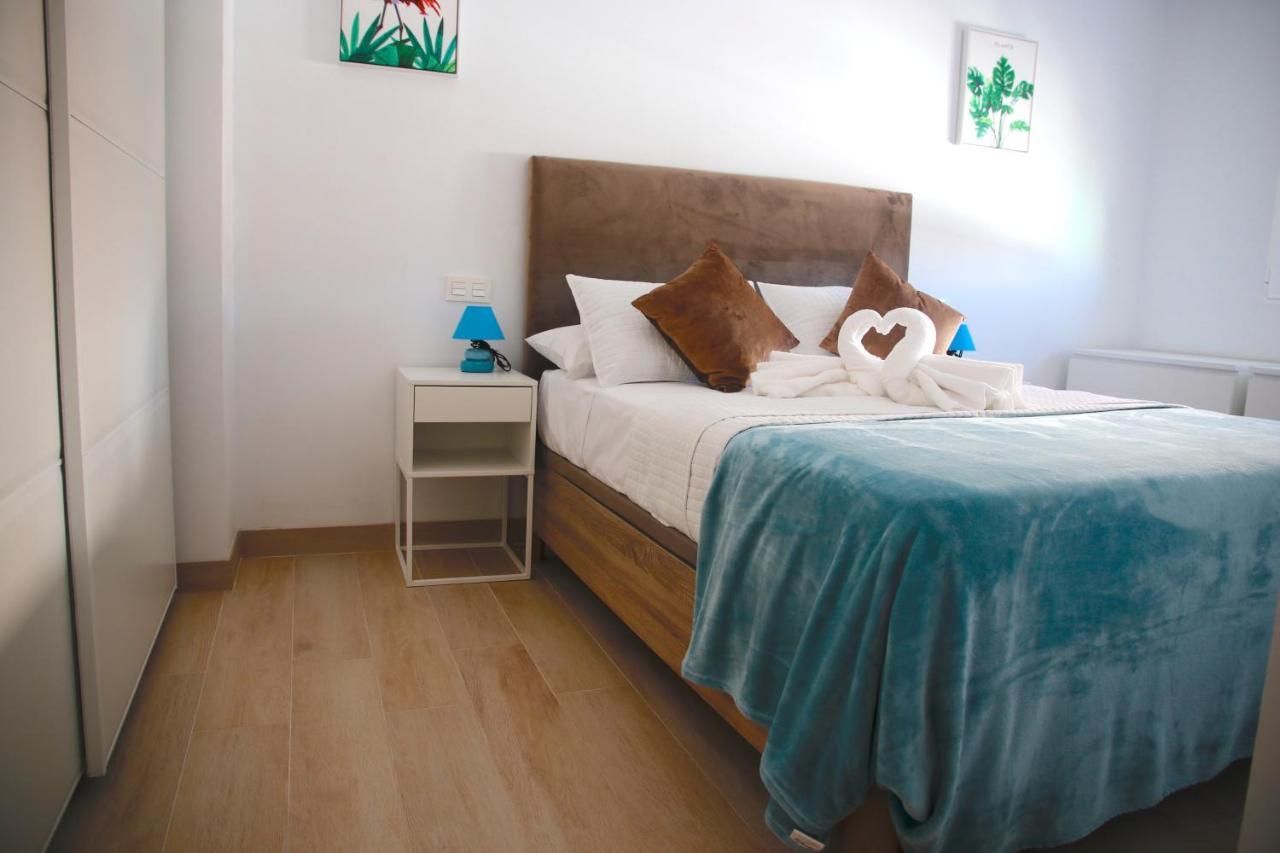 Un dormitorio con cama, mesita de noche, lámpara y cuadros en la pared.