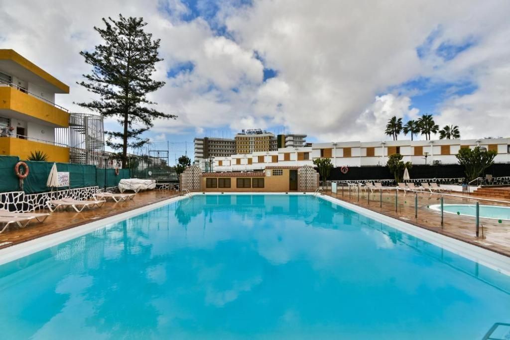 Una gran piscina está rodeada de sillas y un edificio.