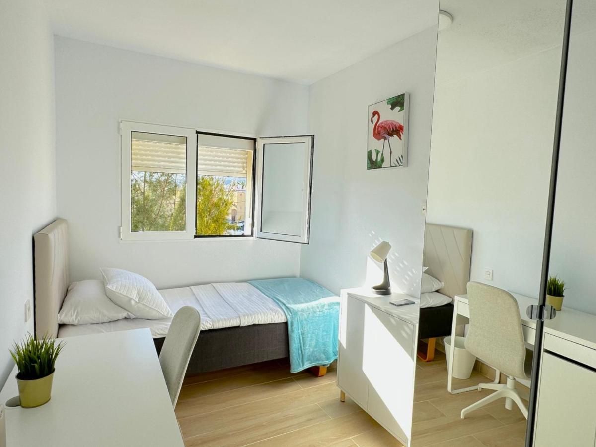 Un dormitorio con una cama individual, escritorio, silla y espejo.