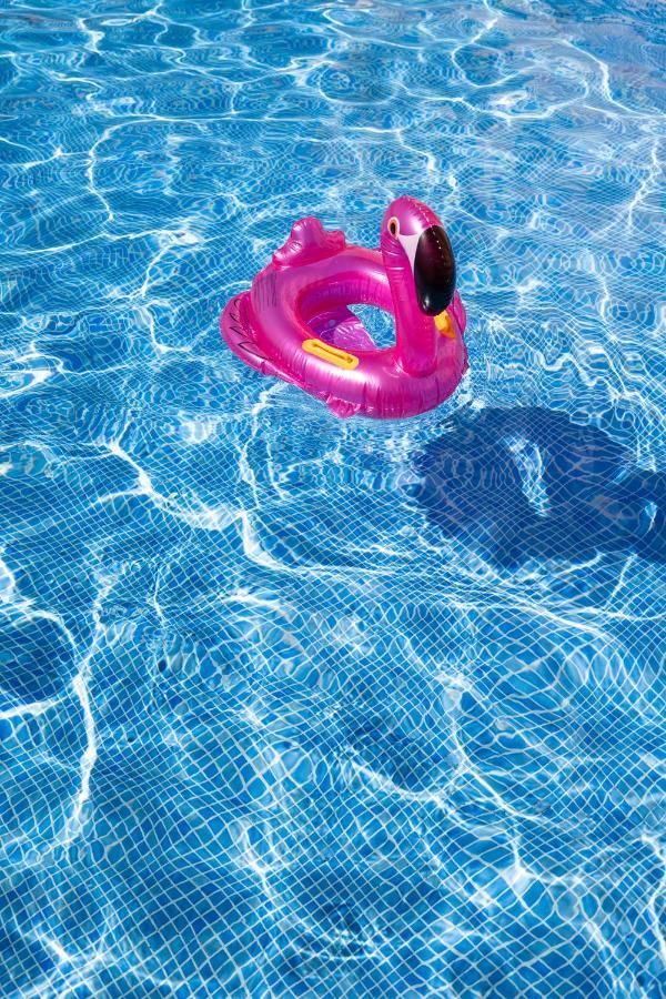 Un flotador de flamenco rosa flota en una piscina.