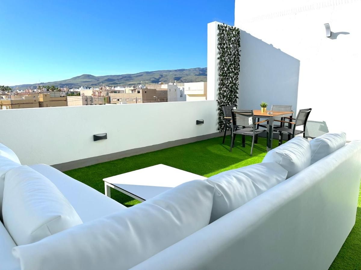 Un patio con un sofá blanco y una mesa y sillas.