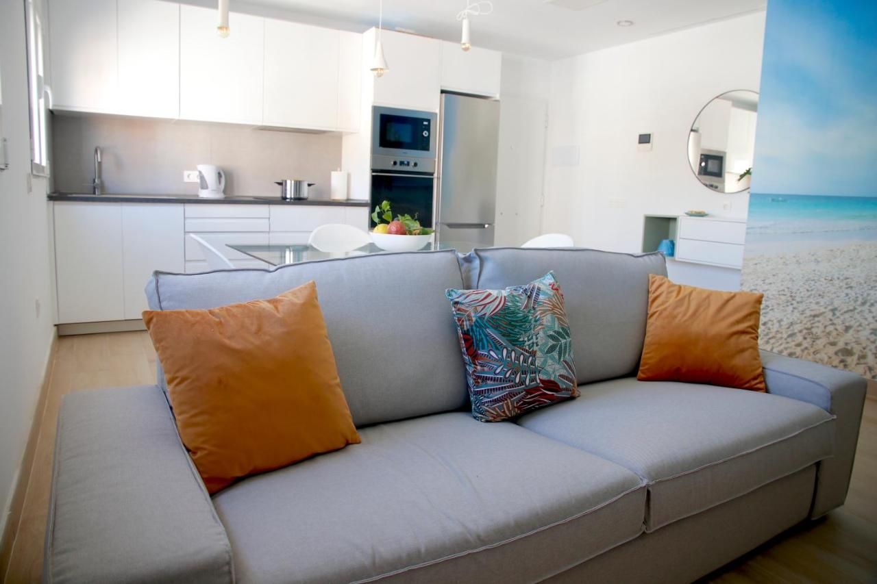 Una sala de estar con un sofá gris y almohadas naranjas.