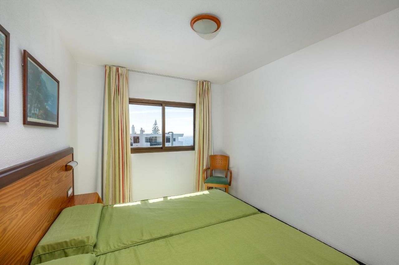 Un dormitorio con una cama verde y una silla.