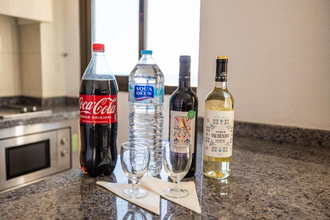 Una botella de Coca Cola, una botella de agua y dos copas de vino están sobre un mostrador.