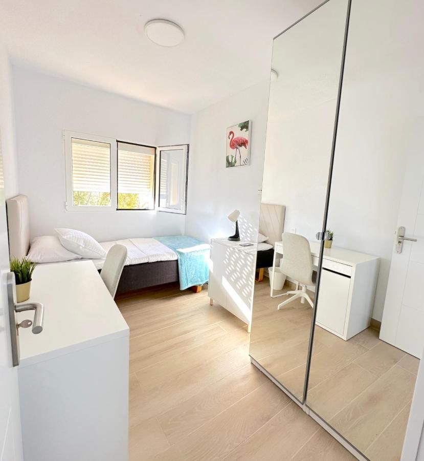 Un dormitorio con dos camas, un escritorio y un espejo.