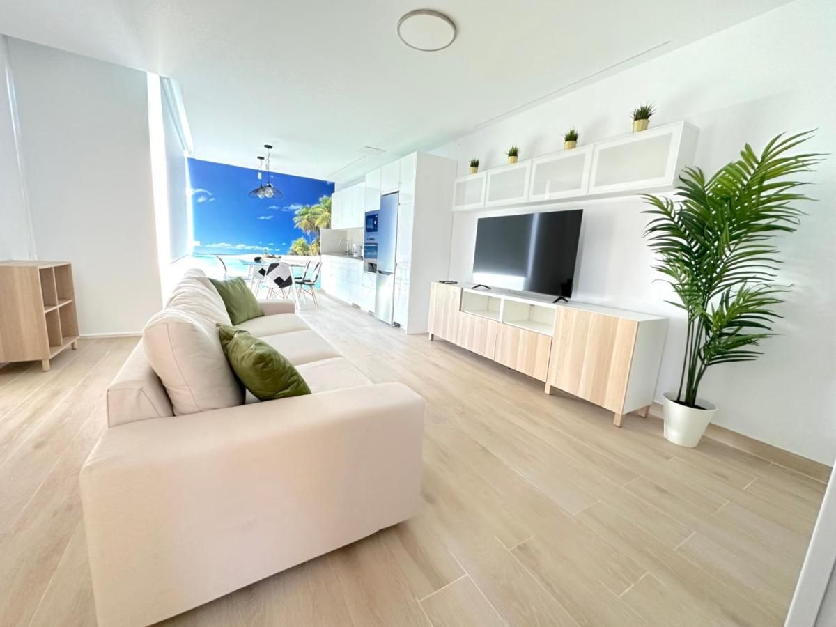 Una sala de estar con un sofá, televisión y una planta en maceta.