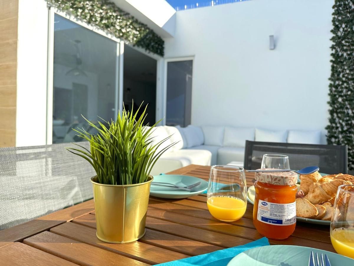 Una planta en maceta reposa sobre una mesa junto a un vaso de jugo de naranja.