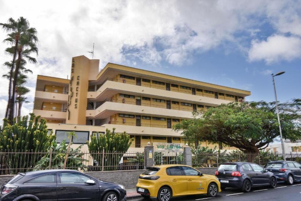 Un gran edificio con muchos coches aparcados delante.