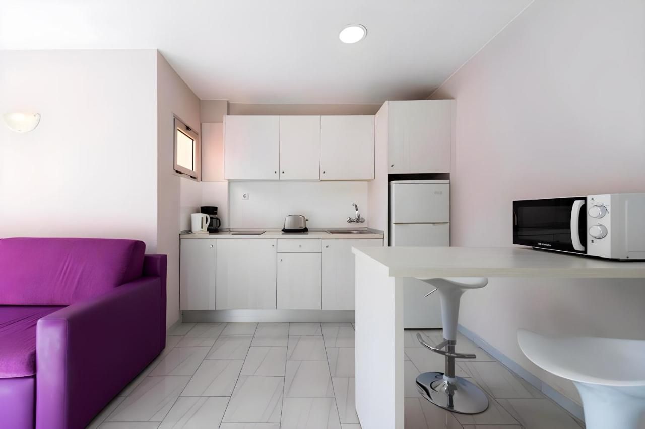 Una cocina con gabinetes blancos y un sofá morado.