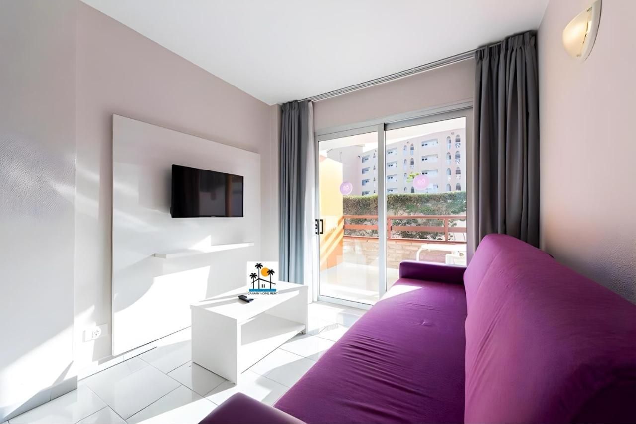 Una sala de estar con un sofá morado y un televisor de pantalla plana.