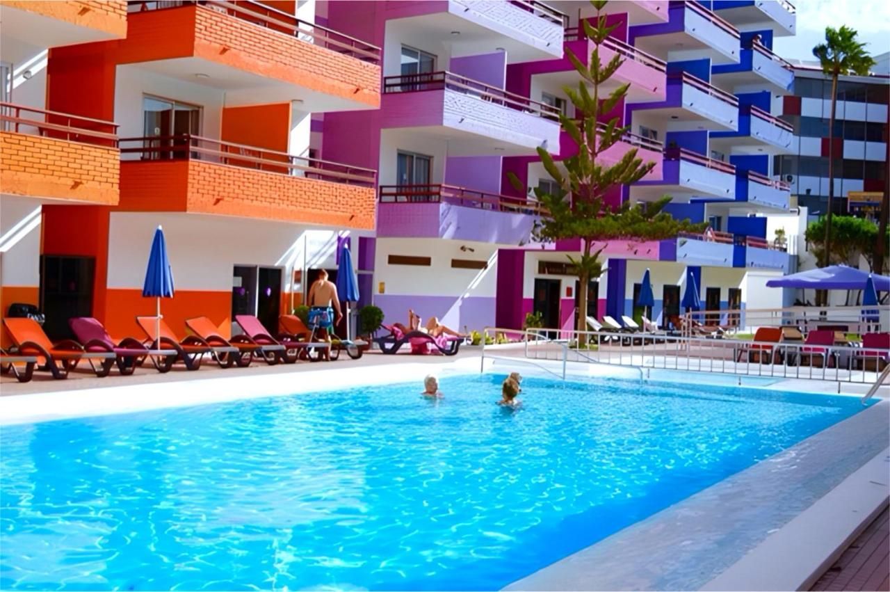 Dos personas están nadando en una piscina frente a un hotel.