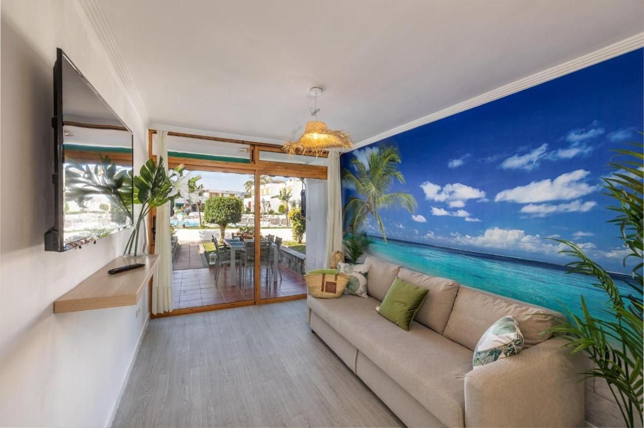 Una sala de estar con un sofá, televisión y una imagen del océano en la pared.