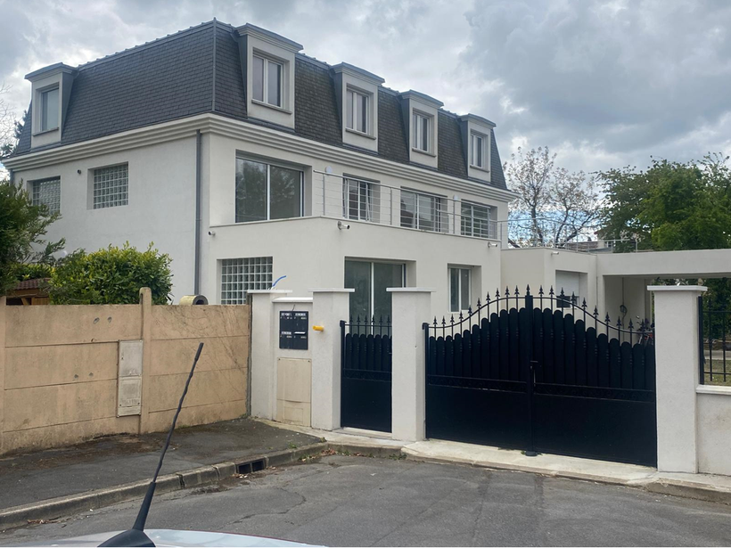 Maison de maître avec toit en ardoise, façade blanche et extension avec toit terrasse