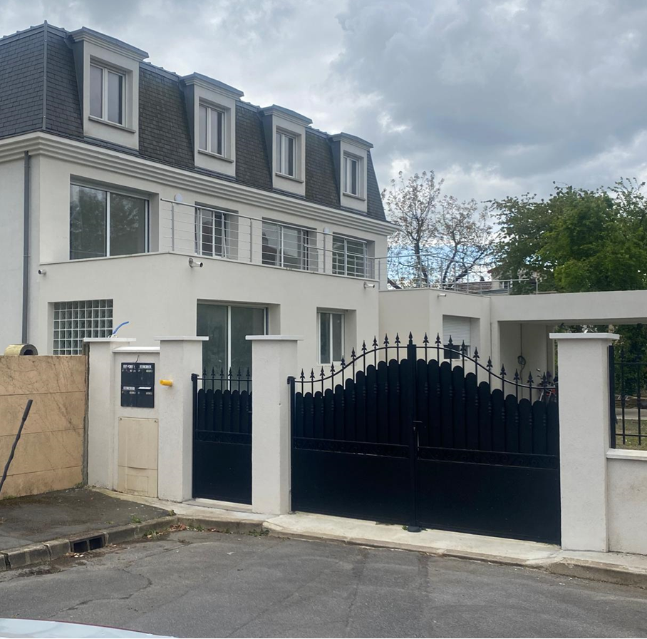 Maison de maître avec toit en ardoise, façade blanche et extension avec toit terrasse
