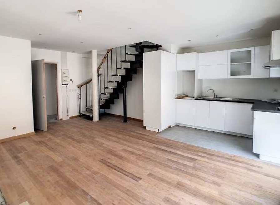 Cuisine ouverte sur une pièce à vivre avec parquet et escaliers