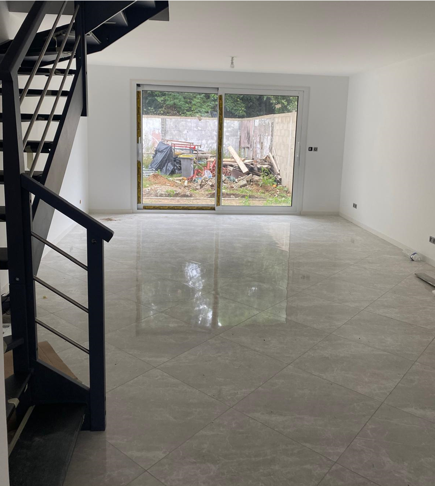 Séjour lumineux sans meuble avec sol carrelé et grande baie vitrée