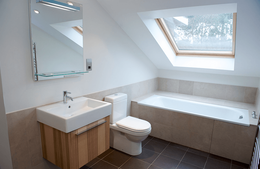 Salle de bains sous des combles avec baignoire et toilettes