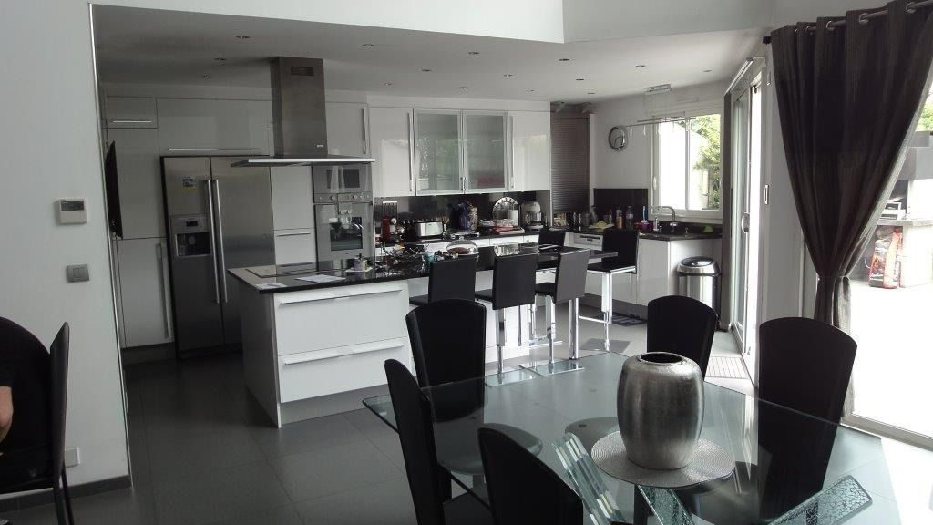 Cuisine américaine moderne noire et blanche avec îlot central et ouverte sur une salle à manger