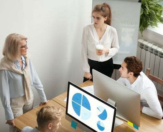 Un grupo de personas está sentada alrededor de una mesa mirando una pantalla de computadora.