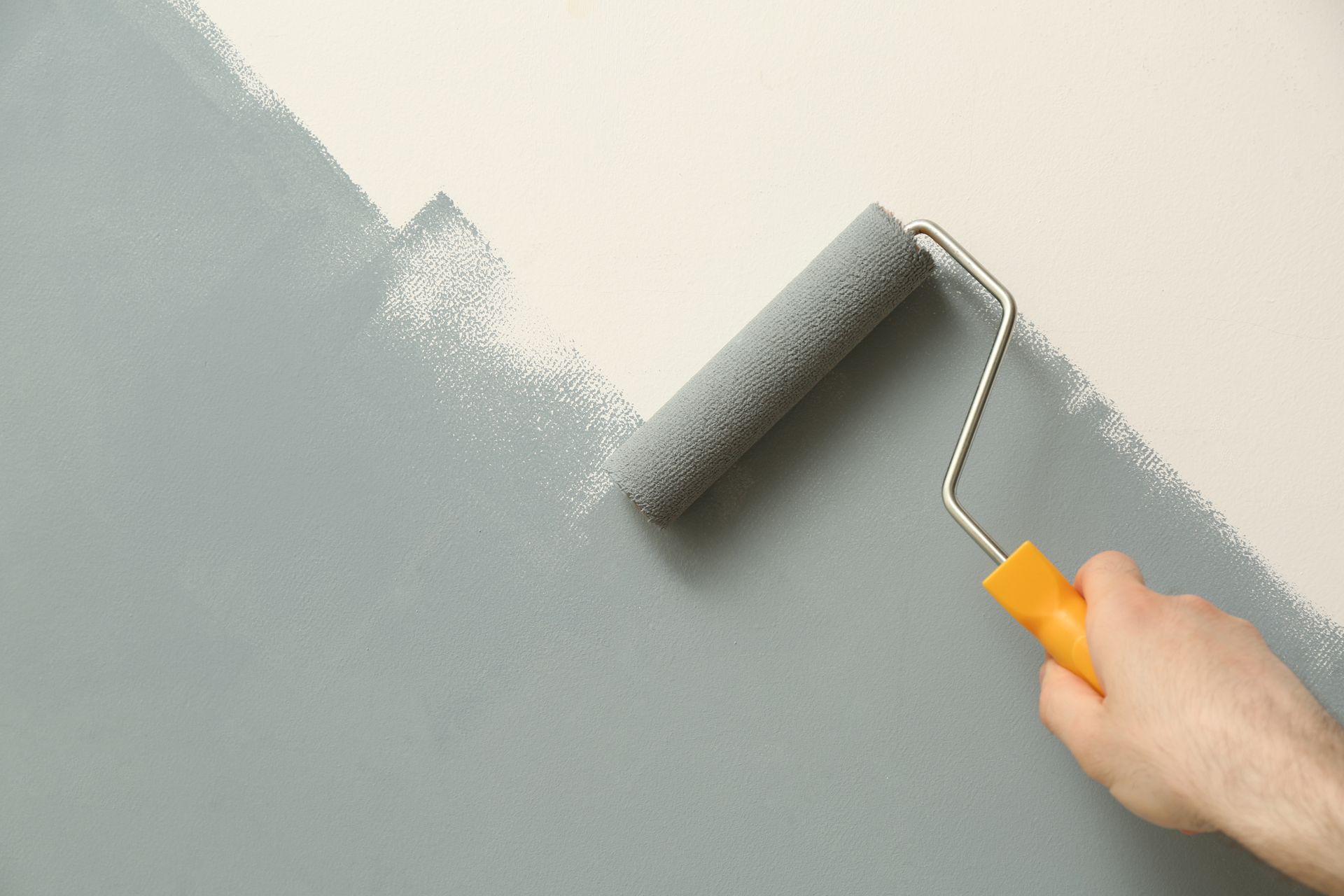 Ouvrier en veste bleue lissant du plâtre sur un mur à l'aide d'une truelle et d'une taloche