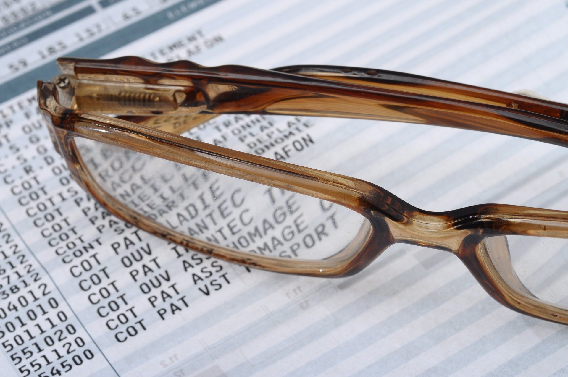 Des lunettes posées sur un document imprimé contenant des informations financières, notamment du texte et des chiffres.