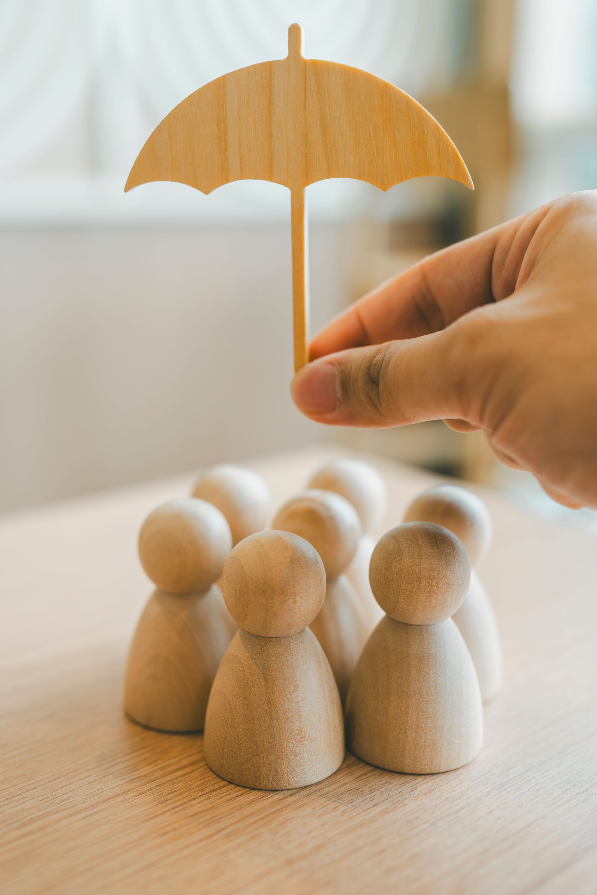 Main tenant un parapluie en bois au-dessus de figurines en bois.