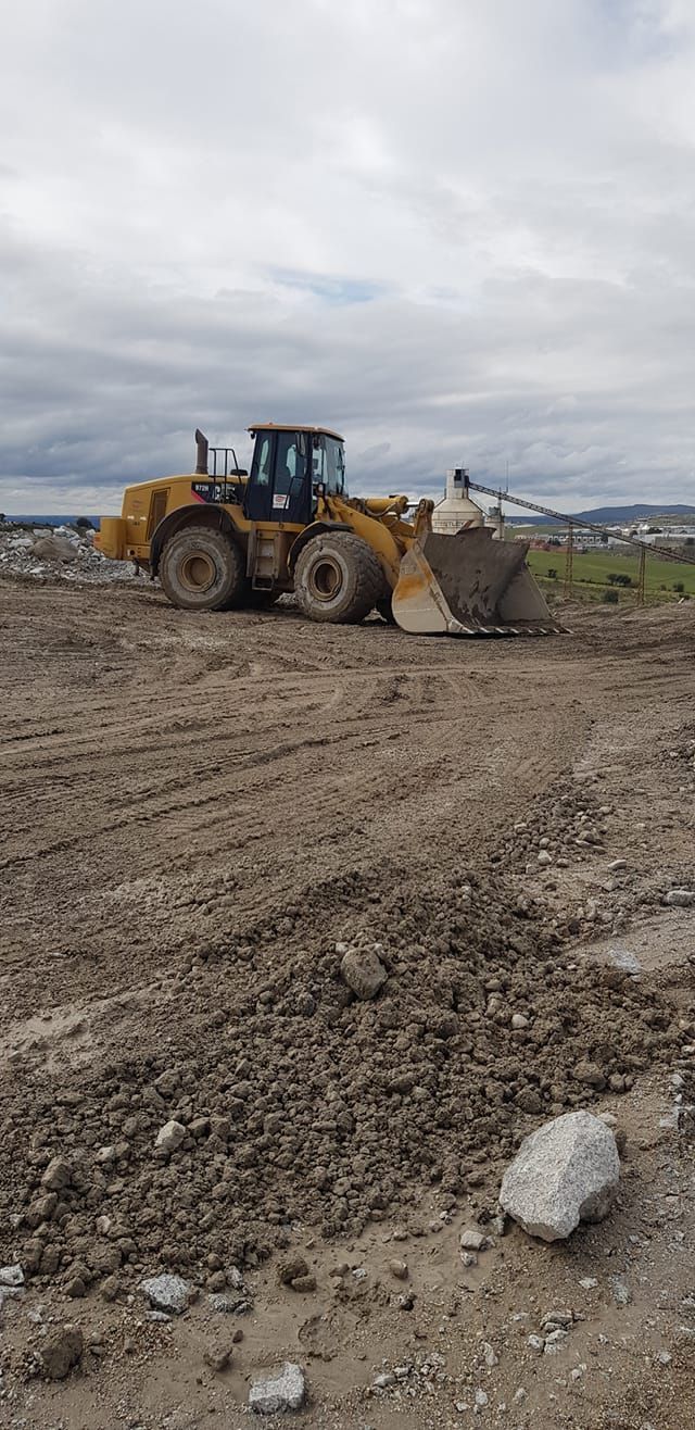 Una excavadora avanza por un campo de tierra.