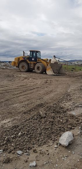 Una excavadora avanza por un campo de tierra.