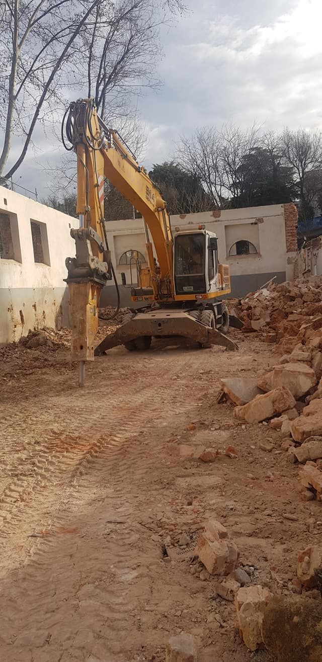 Una excavadora amarilla está cavando un hoyo en un campo de tierra.