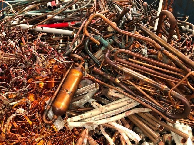 Chatarra de cobre en una pila, con tubos, cables y varias formas en tonos de marrón y naranja.