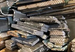 Pila de núcleos de radiador de aluminio, probablemente chatarra, con superficies perforadas.