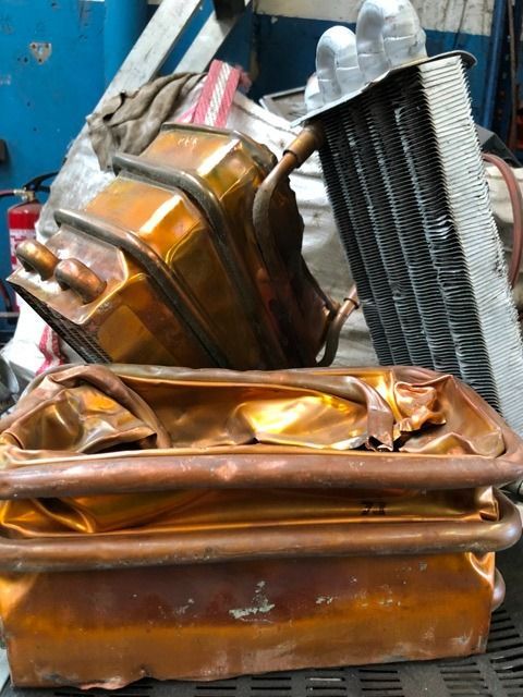 Montón de radiadores y tuberías de cobre y aluminio triturados, posiblemente chatarra.