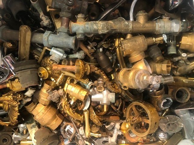 Pila de piezas de plomería de latón, incluidas tuberías, válvulas y accesorios, en varias formas y tamaños.