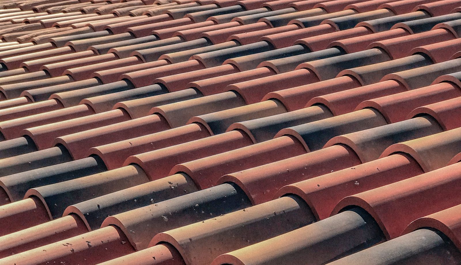 Close-up of red clay roof tiles with rows of dark curved ridges