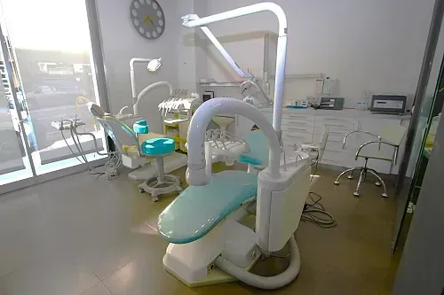 Sillón dental en consultorio limpio y equipado, con buena iluminación y ventana.