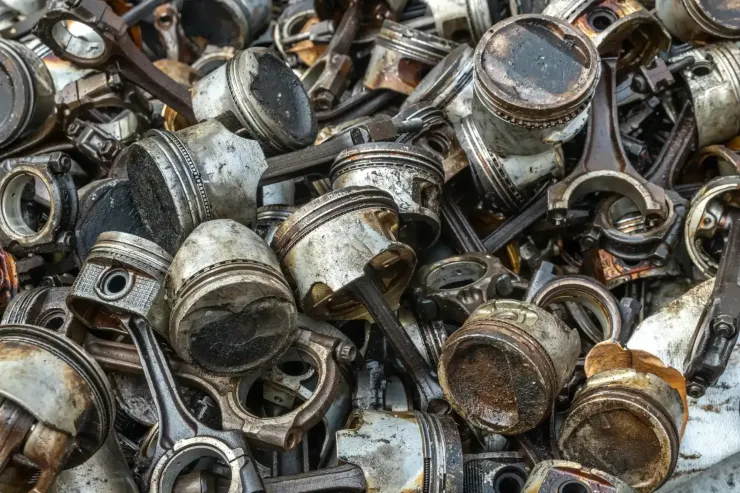 Montón de pistones y bielas de motor usados, cubiertos de aceite y suciedad.