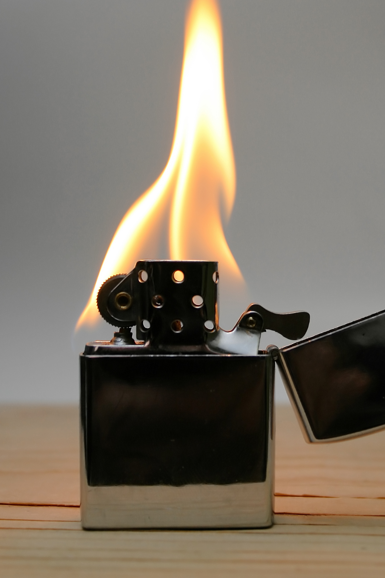 Un encendedor Zippo se enciende sobre una mesa de madera.