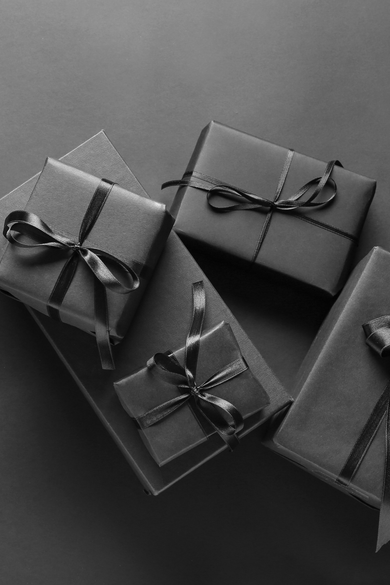 Una fotografía en blanco y negro de una pila de regalos envueltos en negro con moños.