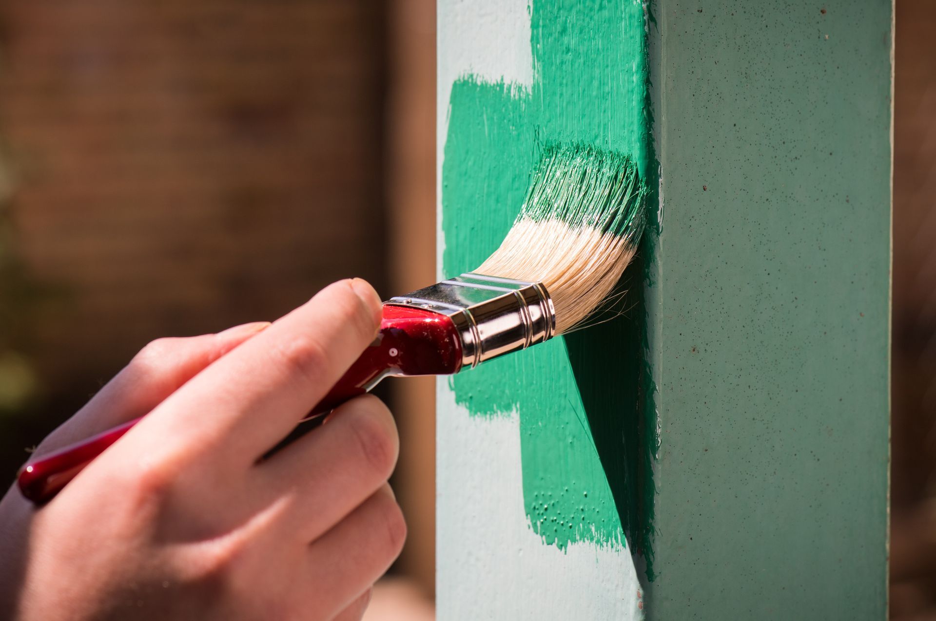 Una persona está pintando un poste verde con un pincel.