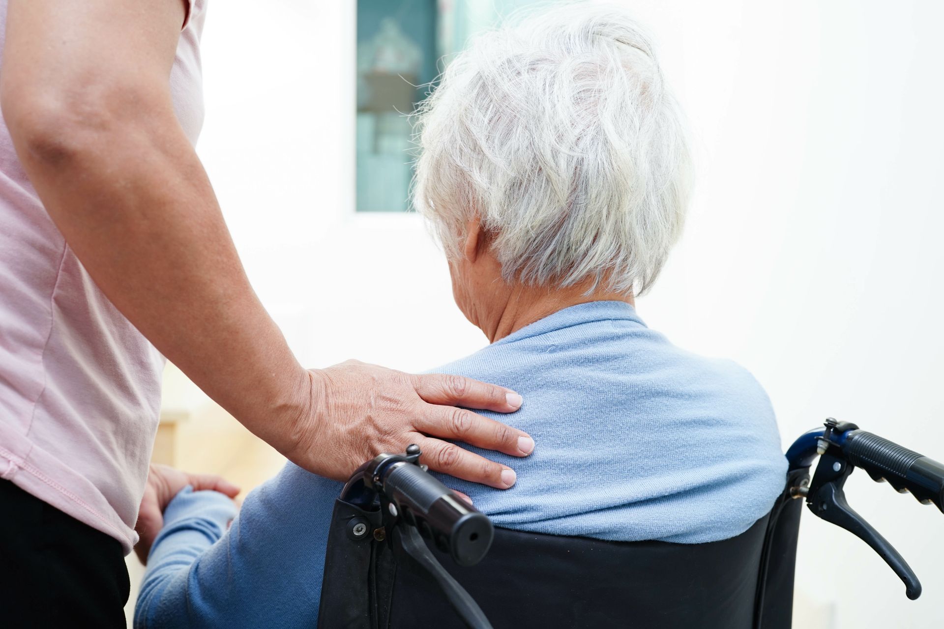Une personne en fauteuil roulant avec une main posée sur son épaule