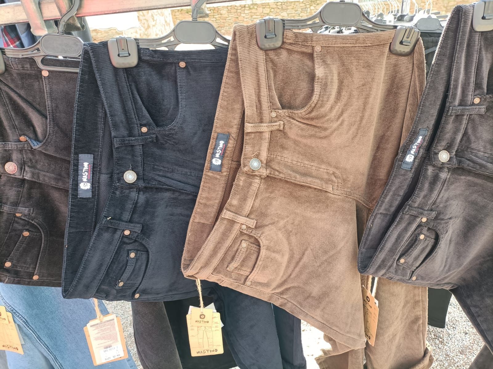Un primer plano de una fila de pantalones de pana de diferentes colores.